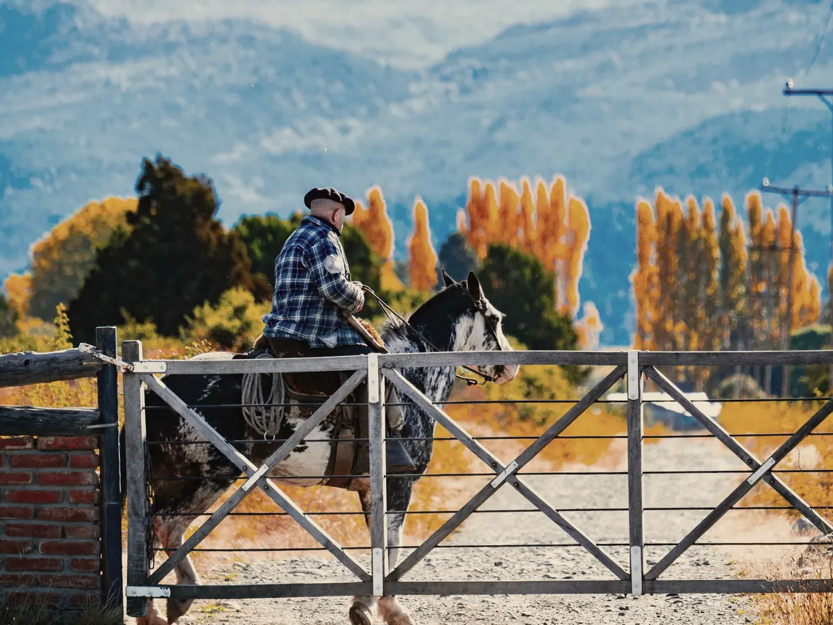 A gaucho on horseback at a gate in Trevelin, Patagonia, Argentina. Holding image